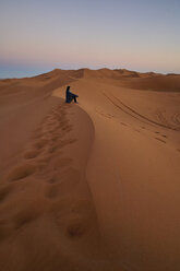Morocco, woman sitting on desert dune at twilight - EPF00509
