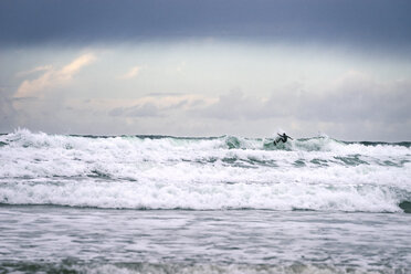 Entfernte Ansicht von Person Surfbrett auf Wellen im Meer gegen Himmel - CAVF60477