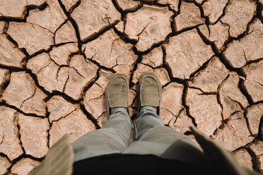 Low section of man standing at barren landscape - CAVF60489