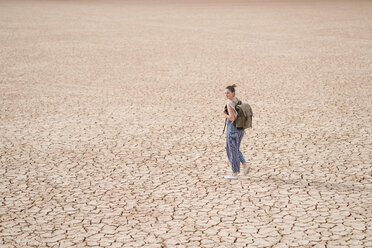 Side view of woman with backpack walking on barren landscape - CAVF60494