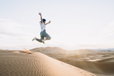 Happy woman jumping at Merzouga desert against sky - CAVF60511