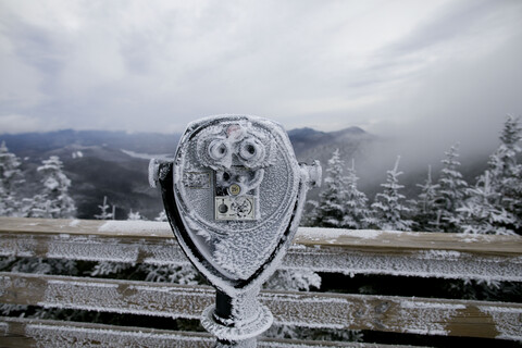 Frozen coin operated binoculars at observation point against mountains stock photo