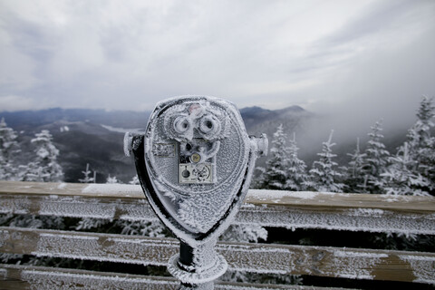 Gefrorene Münzferngläser am Beobachtungspunkt gegen Berge, lizenzfreies Stockfoto