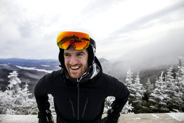Fröhlicher Mann in Skikleidung vor der Landschaft bei nebligem Wetter - CAVF60522