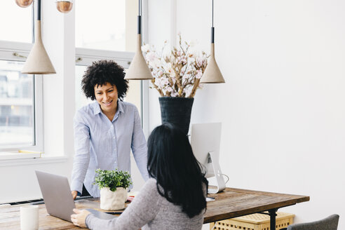 Businesswomen discussing over laptop computer at desk in office - CAVF60572