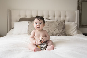 Full length of cute shirtless baby boy with stuffed toy sitting on bed at home - CAVF60614