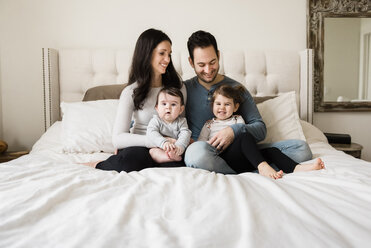 Glückliche Familie auf dem Bett sitzend zu Hause - CAVF60617
