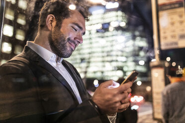 UK, London, Geschäftsmann, der nachts auf dem Weg zur Arbeit sein Telefon überprüft - WPEF01192