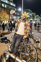 UK, London, man taking a selfie while commuting at night in the city - WPEF01211