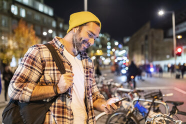 UK, London, Mann pendelt nachts in der Stadt und schaut auf sein Handy - WPEF01212