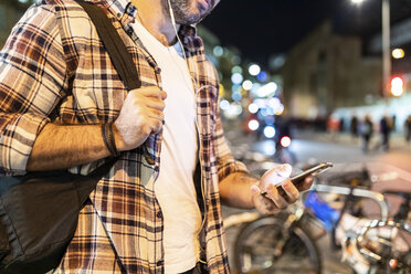 UK, London, close-up of man commuting at night in the city and using his phone - WPEF01213