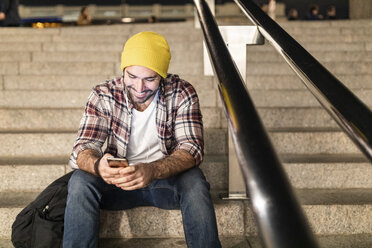 UK, London, Mann sitzt auf einer Treppe und schaut auf sein Handy während einer nächtlichen Fahrt - WPEF01214