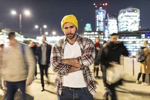 UK, London, Porträt eines Pendlers bei Nacht mit unscharfen Passanten, lizenzfreies Stockfoto