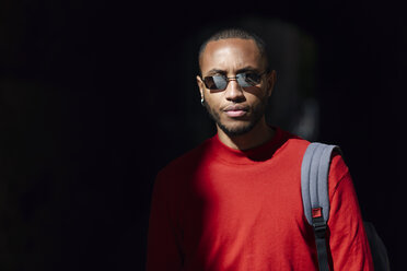 Portrait of young man wearing sunglasses and red pullover - JSMF00701