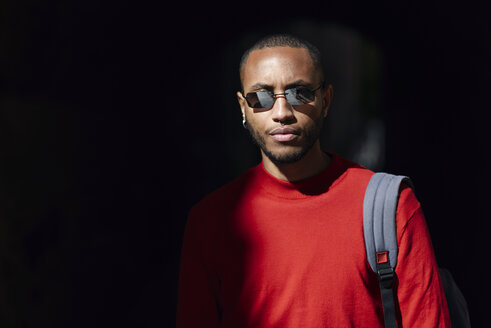 Portrait of young man wearing sunglasses and red pullover - JSMF00701