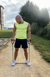 Muskulöser Mann beim Training mit Expander im Freien - MGOF03844