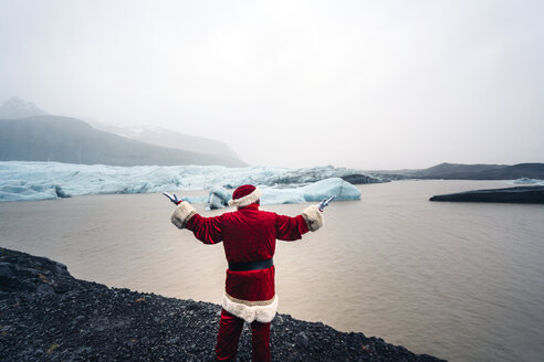 Island, Rückenansicht des Weihnachtsmanns vor einem Gletscher - OCMF00173