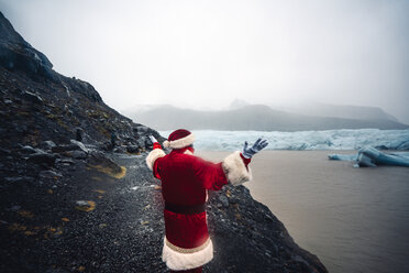 Island, Rückenansicht des Weihnachtsmanns vor einem Gletscher - OCMF00174