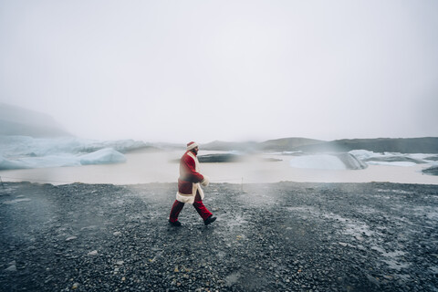 Island, Weihnachtsmann geht in Gletscherlandschaft, lizenzfreies Stockfoto