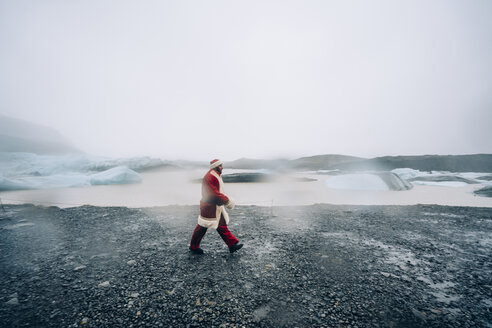 Iceland, Santa Claus walking in glacier landscape - OCMF00176