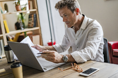 Konzentrierter Geschäftsmann mit Laptop am Schreibtisch - GIOF05073