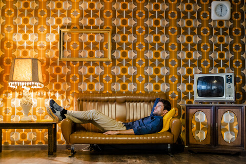 Mann liegend auf Couch in Vintage-Wohnzimmer, lizenzfreies Stockfoto