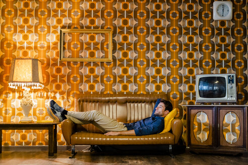 Mann liegend auf Couch in Vintage-Wohnzimmer - GIOF05077