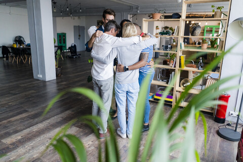 Geschäftsteam kauert im Loftbüro, lizenzfreies Stockfoto