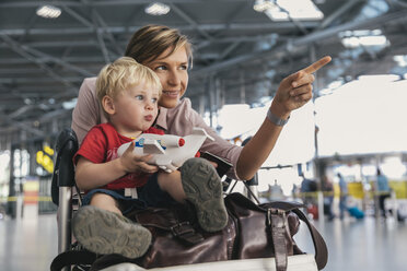 Germany, Cologne, portrait of mother and little son with baggage cart at airport terminal - MFF04714