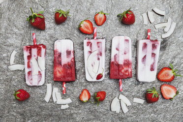 Hausgemachte Erdbeer-Kokosnuss-Eislutscher mit frischen Erdbeeren und Kokosnuss-Scheiben auf Granit - GWF05710