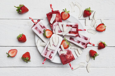 Hausgemachte Erdbeer-Kokosnuss-Eislutscher mit frischen Erdbeeren und Kokosnussscheiben auf dem Teller - GWF05712