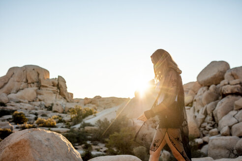 USA, Kalifornien, Los Angeles, Frau geht auf Felsen im Gegenlicht im Joshua Tree National Park - DAWF00846