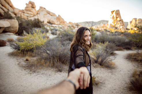 USA, Kalifornien, Los Angeles, Porträt einer lächelnden Frau, die Hand in Hand im Joshua Tree National Park spazieren geht - DAWF00848