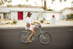 USA, California, Palm Springs, smiling woman riding bicycle on the street - DAWF00869