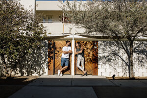 USA, California, Palm Springs, smiling couple standing at house entrance - DAWF00870