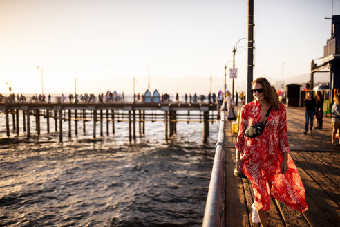 USA, Kalifornien, Santa Monica, lächelnde Frau beim Spaziergang auf dem Pier - DAWF00873