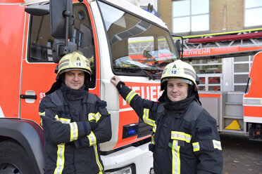 Porträt von zwei zuversichtlichen Feuerwehrleuten vor einem Feuerwehrauto - LYF00842