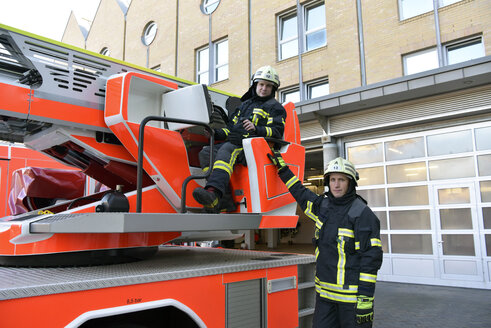 Porträt von zwei Feuerwehrleuten, die an einem Feuerwehrauto üben - LYF00853