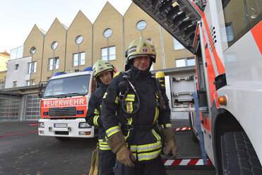 Porträt von zwei Feuerwehrleuten auf dem Hof eines Feuerwehrfahrzeugs - LYF00858