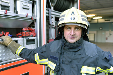 Portrait of confident firefighter in front of fire engine - LYF00862