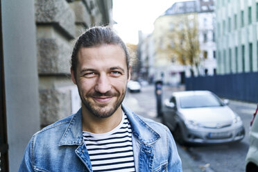 Portrait of bearded young man smiling - FMKF05342