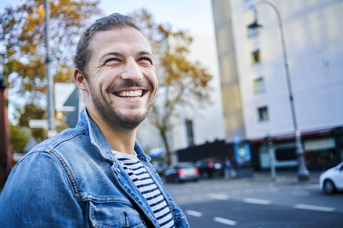 Porträt eines bärtigen jungen Mannes in der Stadt, der lacht, lizenzfreies Stockfoto