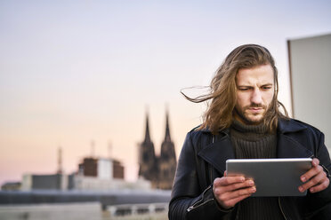 Germany, Cologne, portrait of bearded young man using digital tablet - FMKF05348