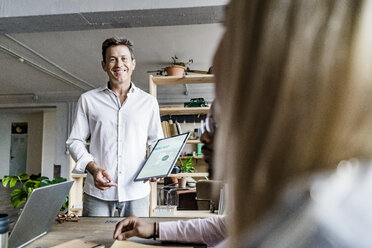 Lächelnder Geschäftsmann, der eine Präsentation in einem Loft-Büro leitet - GIOF05171