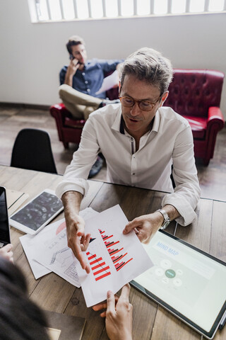 Geschäftsmann beim Analysieren eines Balkendiagramms im Büro, lizenzfreies Stockfoto