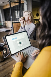 Geschäftsfrau sitzt am Konferenztisch im Loft-Büro und benutzt einen Laptop - GIOF05206