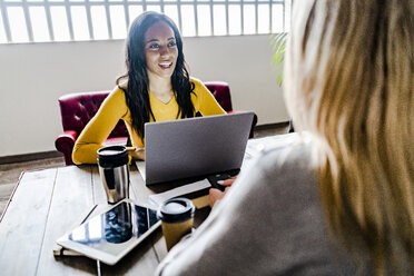 Zwei junge Geschäftsfrauen im Gespräch am Konferenztisch im Büro - GIOF05211