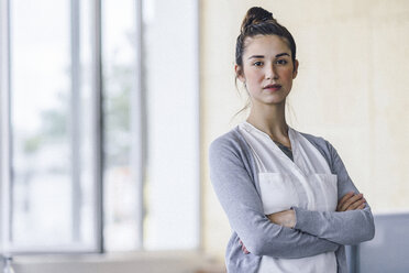 Portrait of a beautiful young woman, standing in office, with arms crossed - RIBF00779