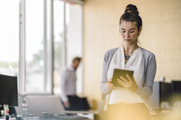 Junge Frau arbeitet im Büro und benutzt ein Tablet - RIBF00782