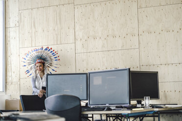 Junge Frau mit indianischem Kopfschmuck, stehend im Büro - RIBF00791